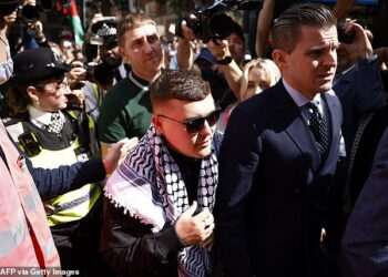 Crowds of Kneecap fans waving Palestinian flags mob court as rapper Mo Chara is bailed after being charged with terrorism offence ‘for displaying Hezbollah flag’