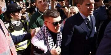 Crowds of Kneecap fans waving Palestinian flags mob court as rapper Mo Chara is bailed after being charged with terrorism offence ‘for displaying Hezbollah flag’